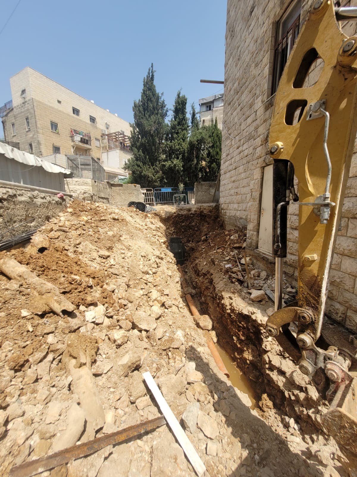 חפירה לאורך קיר אבן ירושלמית — שלב התשתיות בקריית אמשינוב