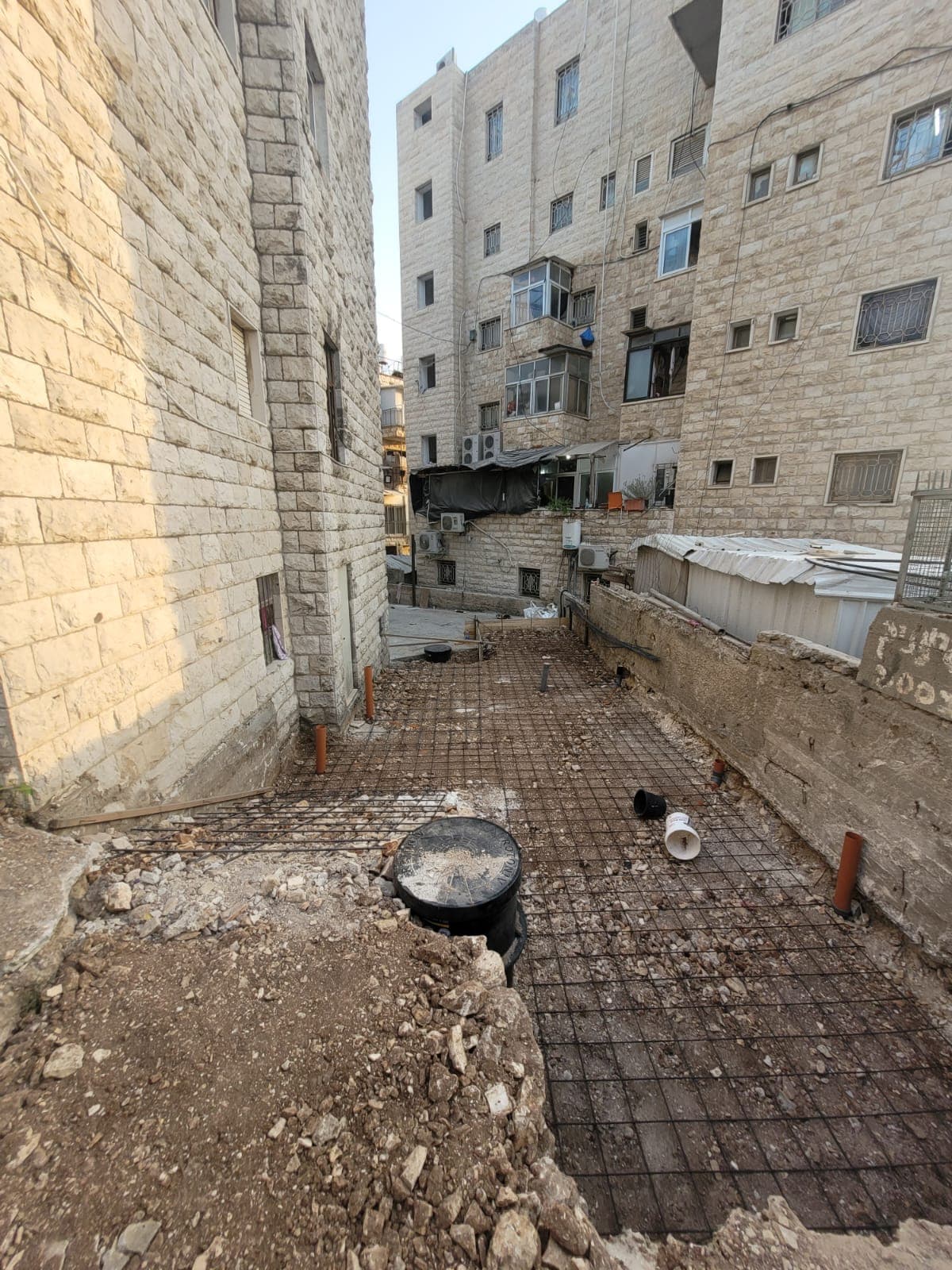 רשת ברזל מזוין נפרשת בסמטה צרה לקראת יציקת בסיס