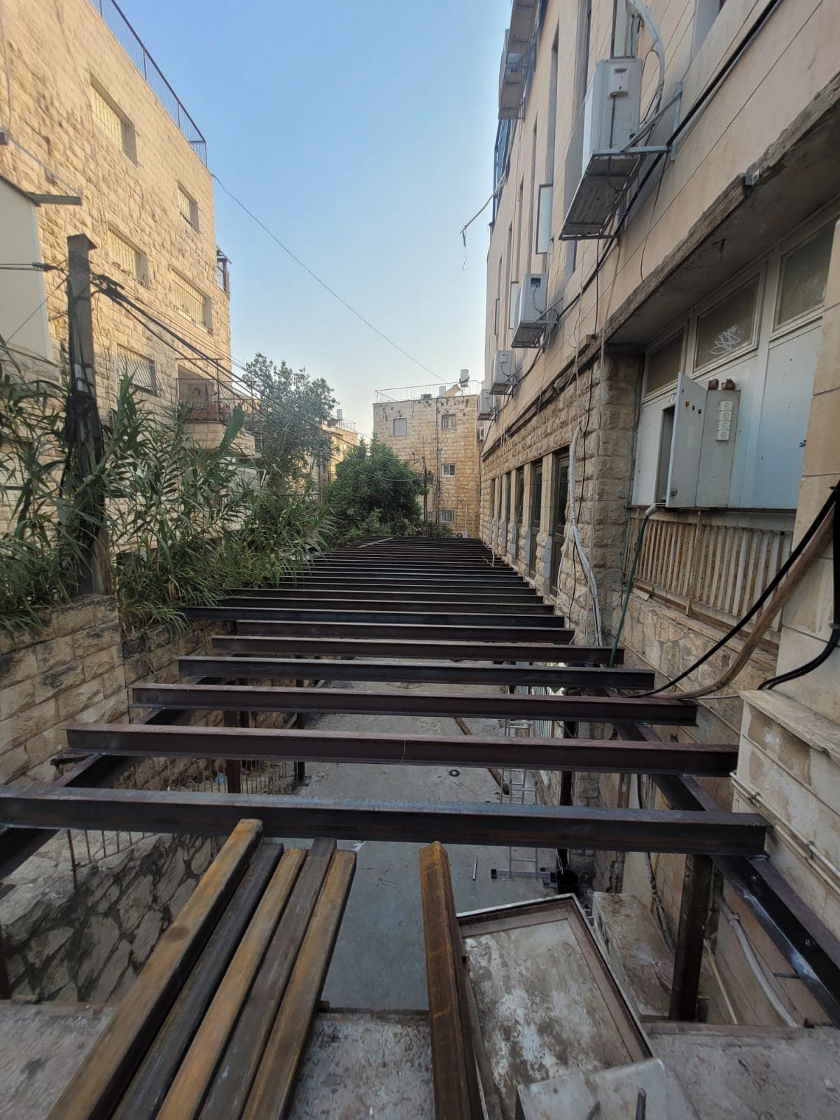 פרספקטיבה של קורות הפלדה המחוברות לאורך הסמטה, בשעת בין־ערביים