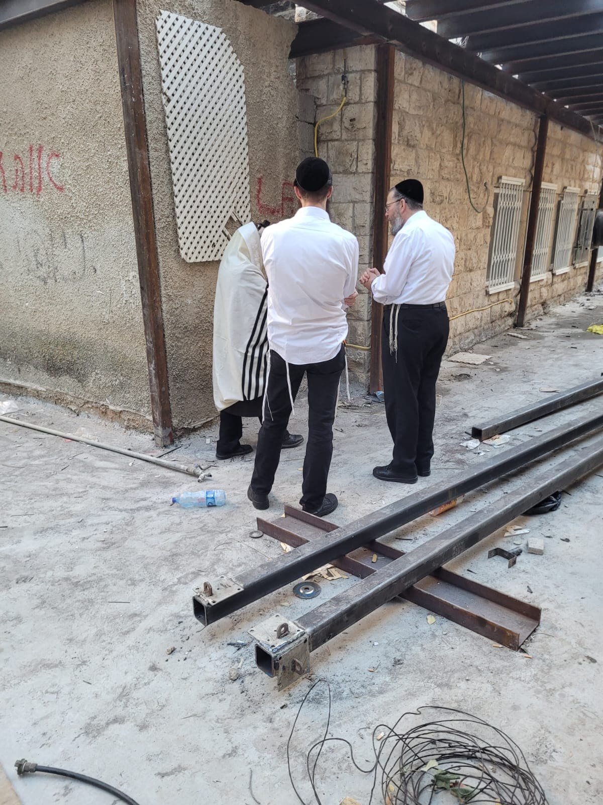 פועלי אתר משוחחים לצד פרופילי פלדה מרובעים חלולים עם פלטות חיבור