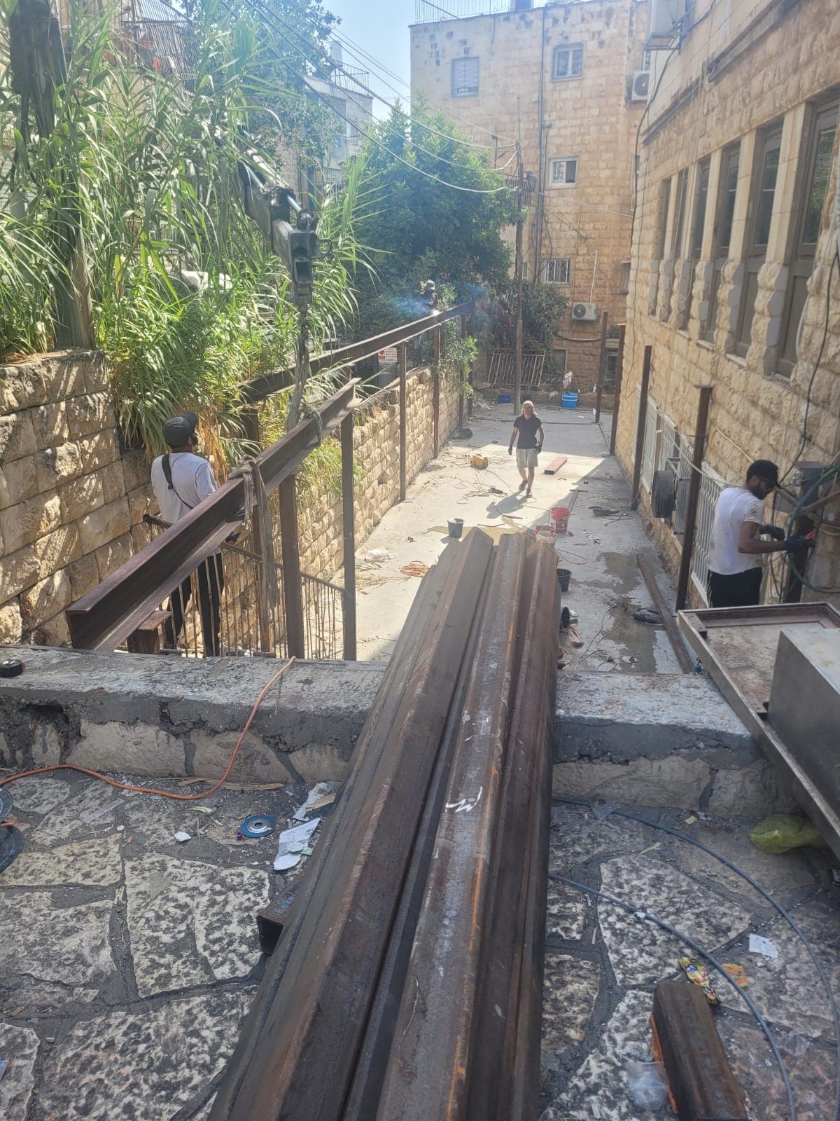 קורות פלדה מוערמות בסמטה צרה לקראת הנפה
