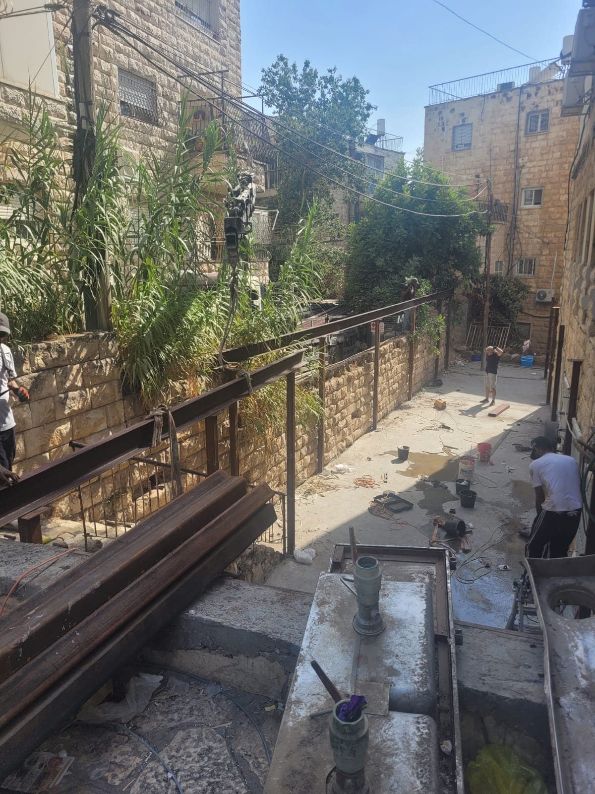 קורות פלדה ארוכות בין שני בניינים, מוכנות להנפה